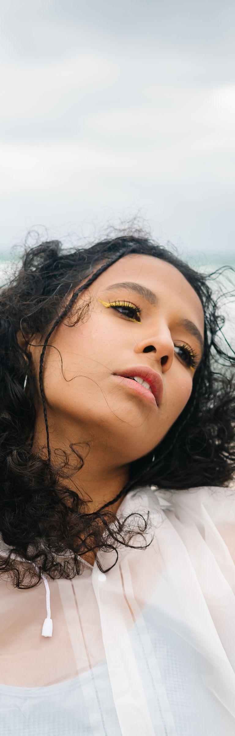 Mujer con el cabello rizado al viento en una playa en verano